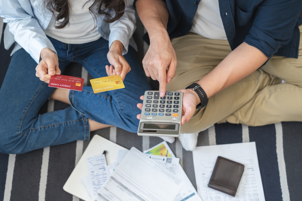 Couple reviewing credit card balances and calculating monthly payments.