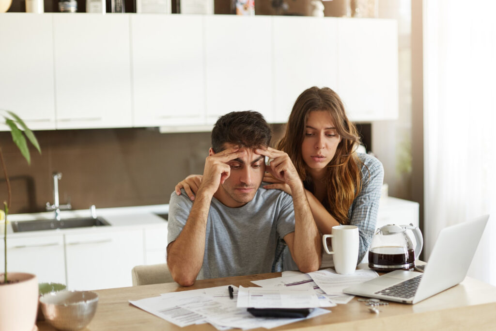 Stressed couple reviewing finances to avoid foreclosure.